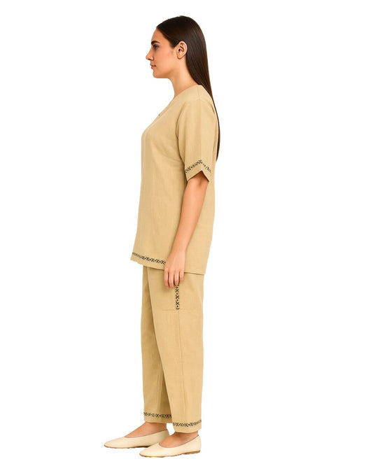 Woman wearing a beige outfit with embroidered details on a white background