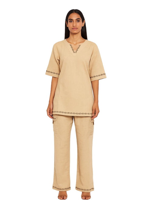 Woman wearing a beige pajama set with intricate details on a white background
