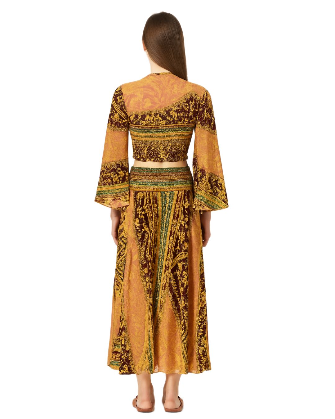 Woman wearing a long, patterned dress with bell sleeves on a white background